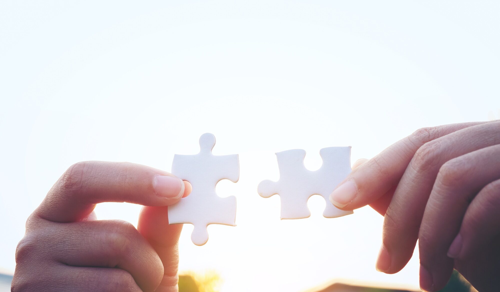 Closeup hand of woman connecting jigsaw puzzle with sunlight, symbol of association and connection